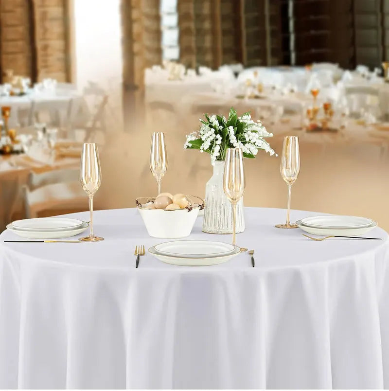 Elegant satin round tablecloths set for an event featuring white floral arrangements and glassware.