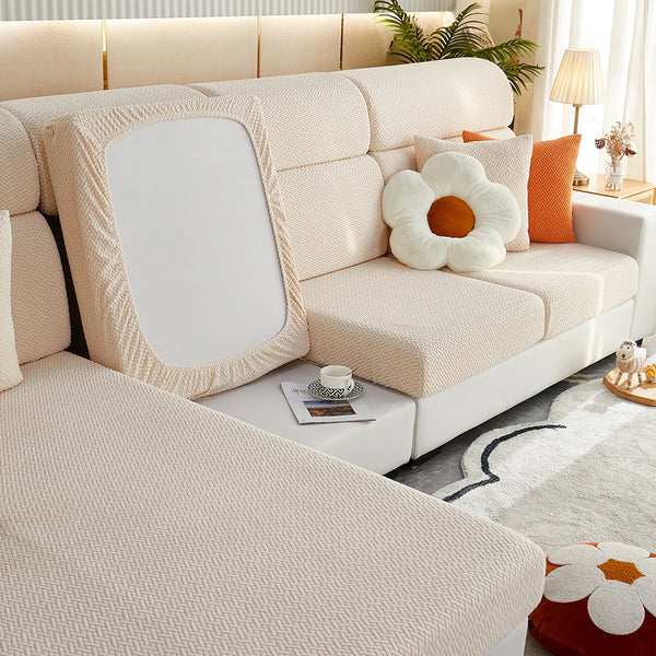A light beige Jacquard sofa slipcover with white cushions and an orange accent pillow.