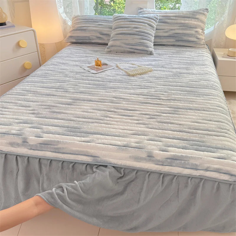 A light gray plush bed skirt linen set with striped bedding and pillows on a bed.
