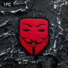 A red glow-in-the-dark smiley face patch embroidered with a mustache and tongue, displayed on a dark, textured surface.