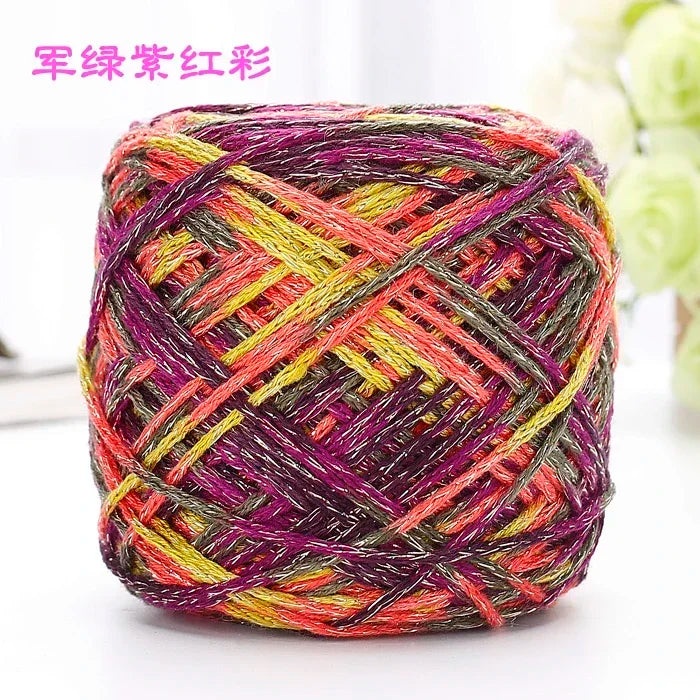 A ball of metallic silk yarn in vibrant shades of pink, yellow, and purple, showing a tightly twisted texture.