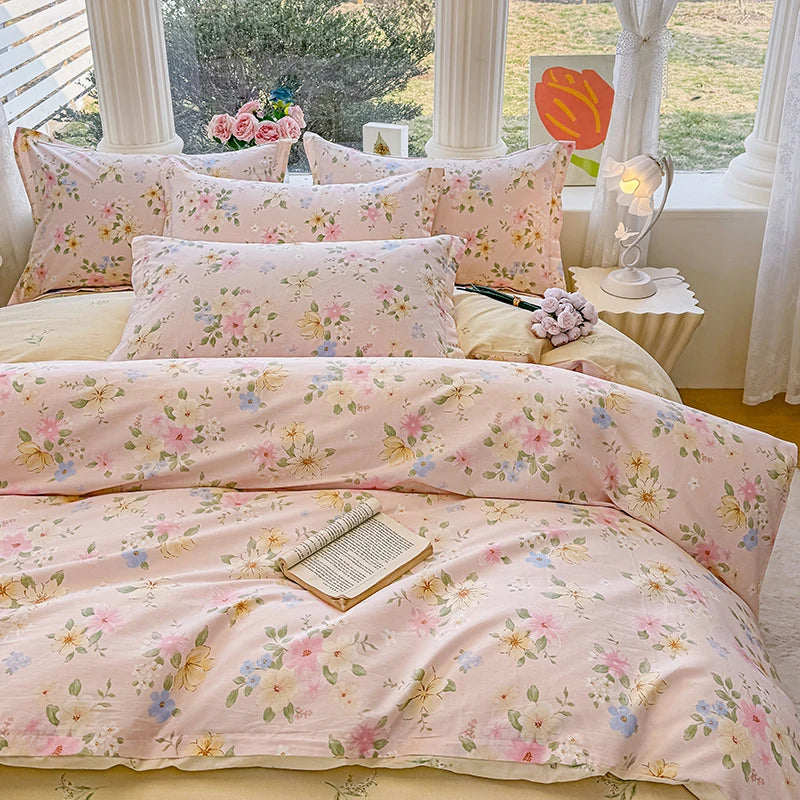 A pink floral duvet cover and pillow set displayed on a bed with white columns and natural light.