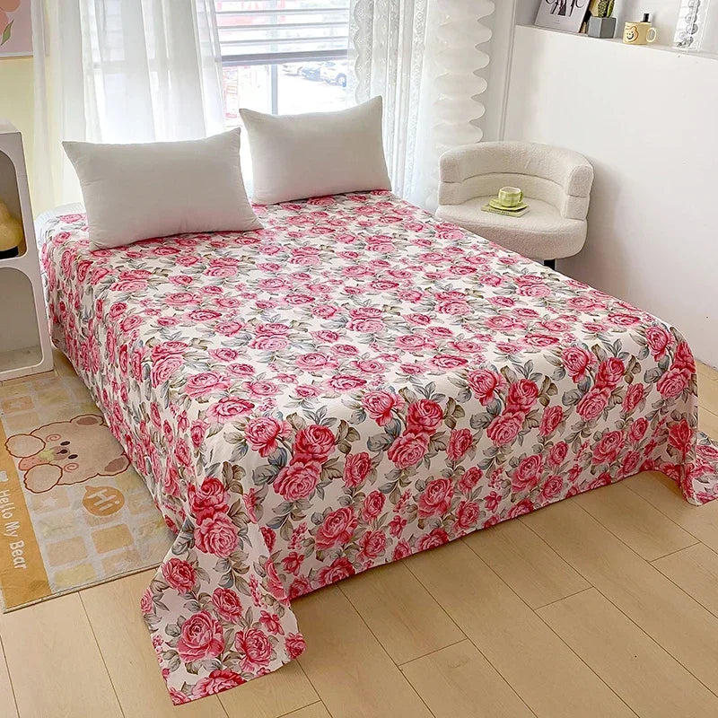 Red floral print flat bed sheets displayed on a bed with white pillows and sheer curtains.