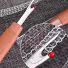 A precision stainless steel sewing needle kit with a leather-wrapped handle and a clear magnifying lens is shown on a dark gr