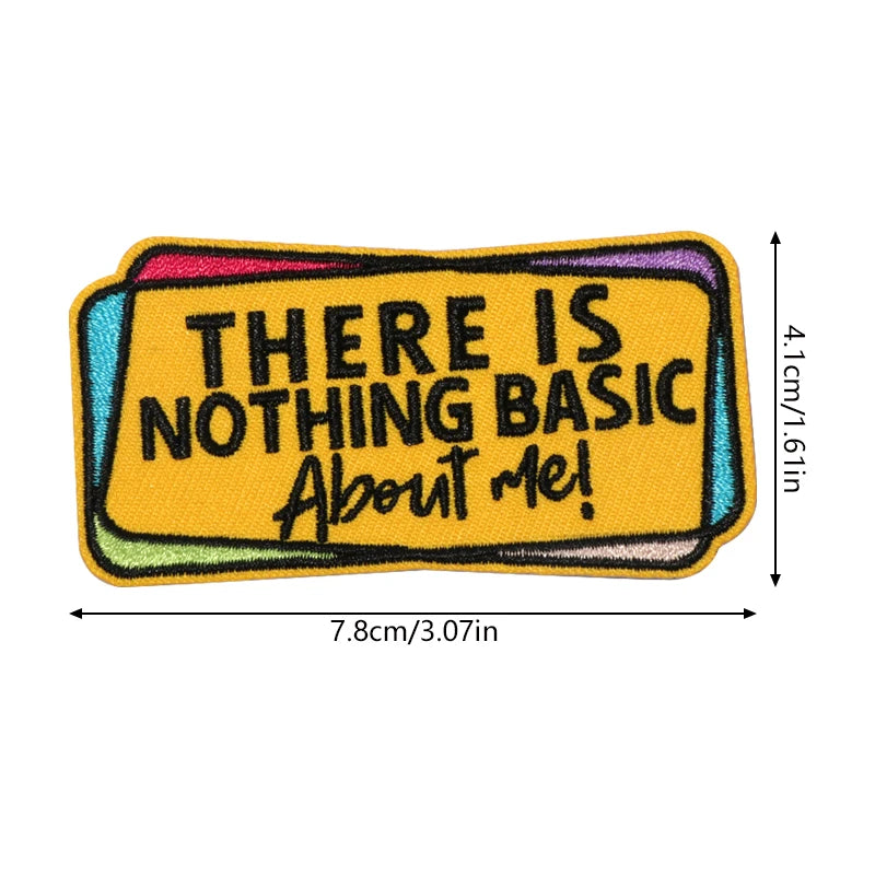 A rectangular embroidered patch with yellow text on a purple background that reads There is nothing basic about me