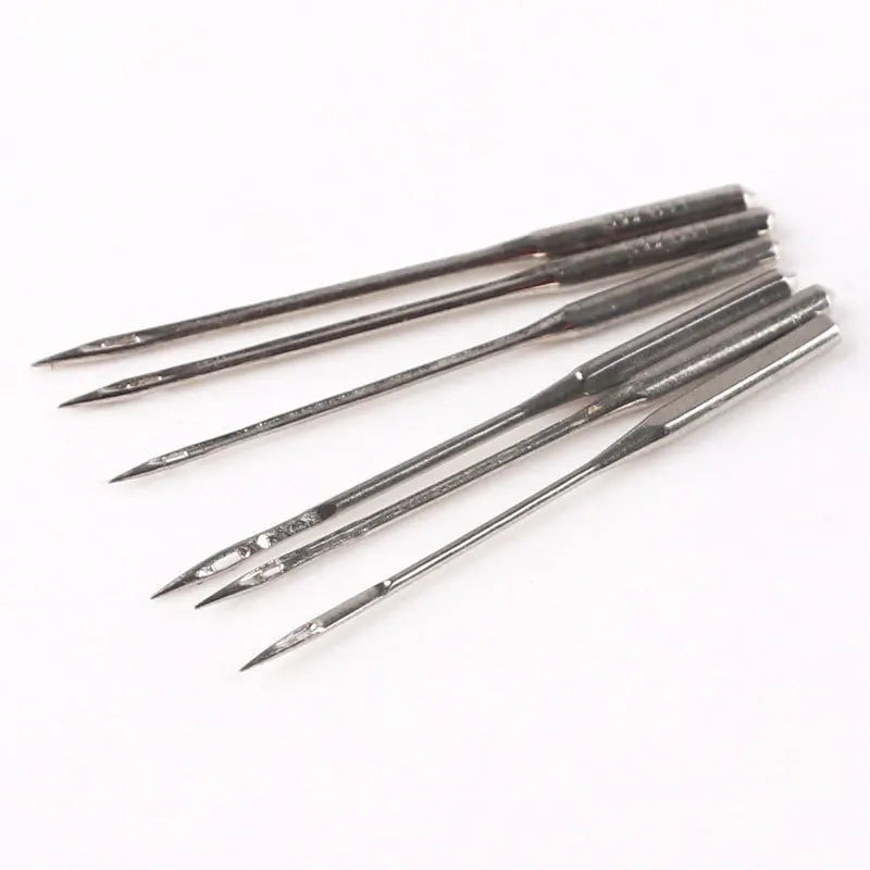 A set of sharp, silver precision sewing threading needles laid diagonally on a white background.