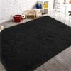 A thick black luxury velvet anti-slip floor mat placed on a wooden floor next to a white brick wall and storage shelves.
