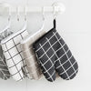 A pair of black and white checkered heat-resistant kitchen oven gloves hanging on a white rack.