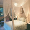 Elegant mosquito netting canopy draped over a bed in a softly lit room.