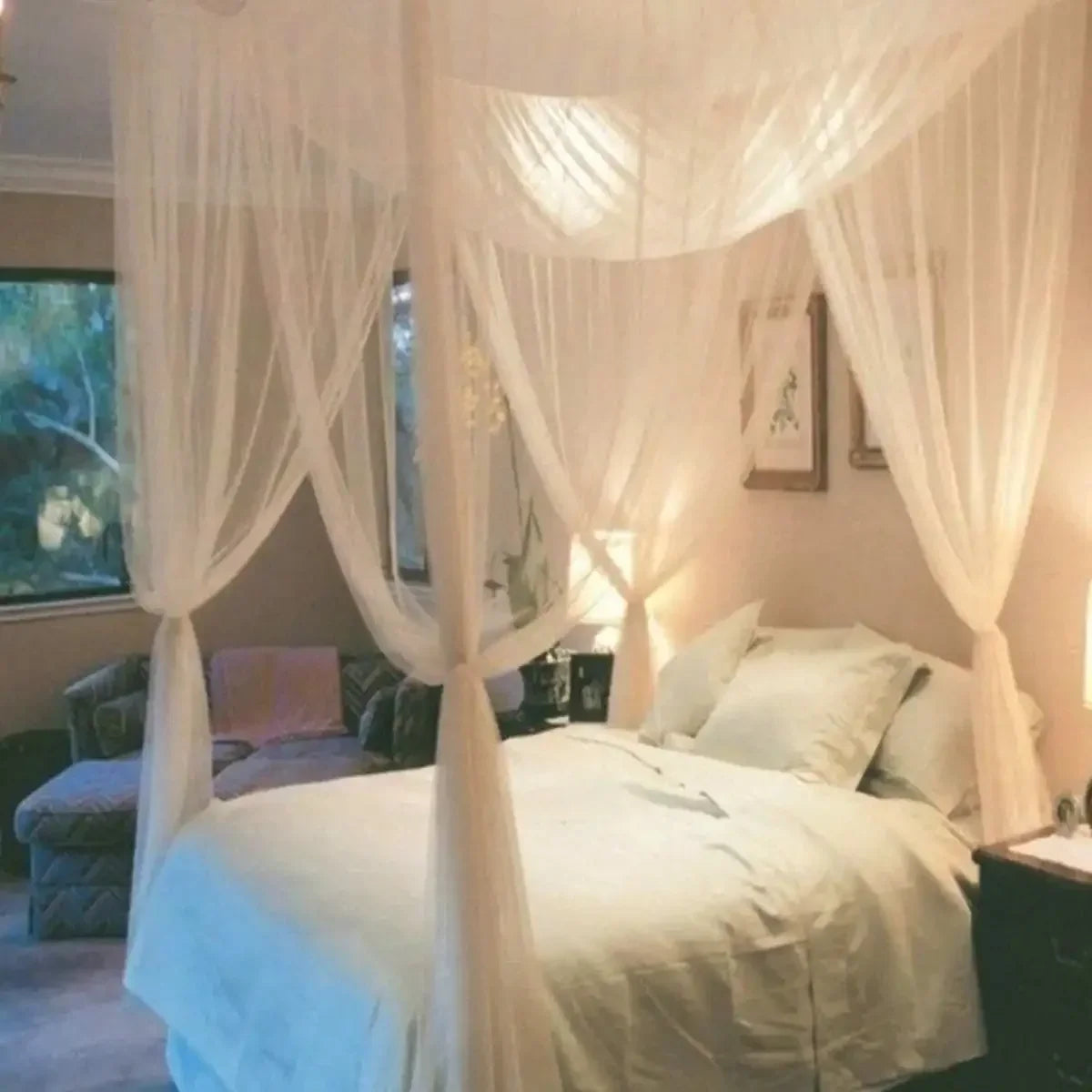 Elegant mosquito netting canopy draped over a bed in a softly lit room.