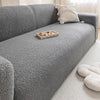A gray textured sofa cover with a light beige throw pillow and a small wooden tray on the seat.