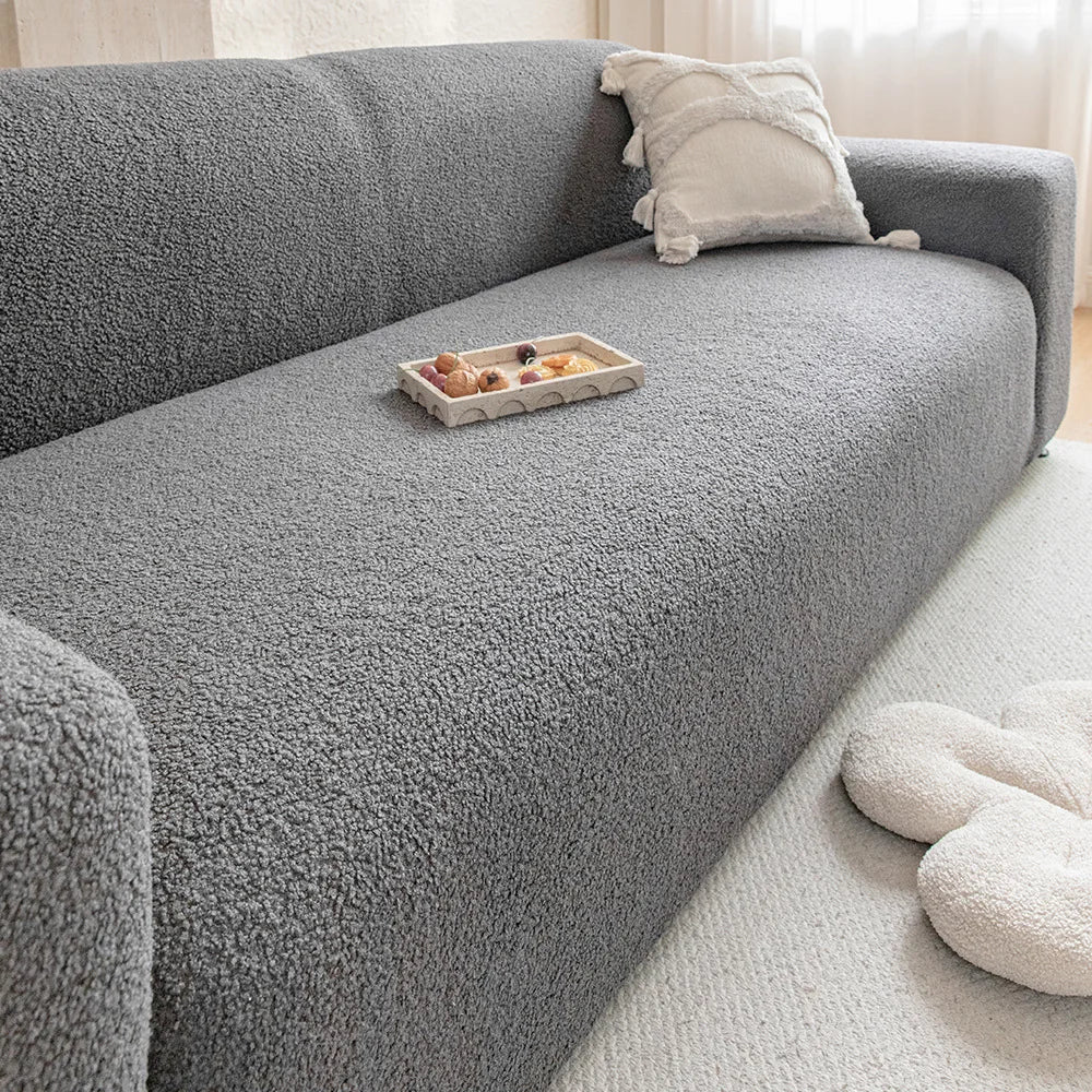A gray textured sofa cover with a light beige throw pillow and a small wooden tray on the seat.