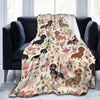 A patterned flannel blanket featuring various dog illustrations in pink and green floral designs draped over a dark sofa.