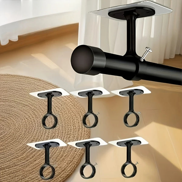 A close-up view of black no-drill adhesive curtain hooks mounted on a white wall.