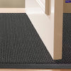 A half-round black non-slip PVC door mat placed on a wooden floor next to a white door frame.