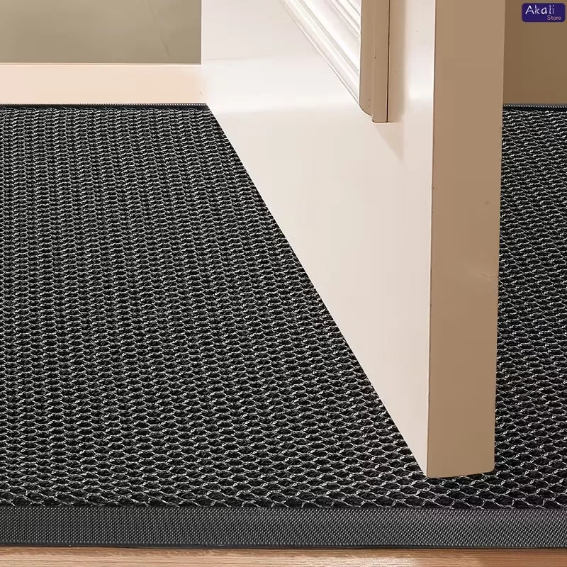 A half-round black non-slip PVC door mat placed on a wooden floor next to a white door frame.