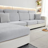 A light gray stretchable chenille sofa cushion cover on a modern sectional sofa with white accents.