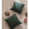 Two dark green tartan plaid decorative throw pillow covers resting on a beige textured surface.