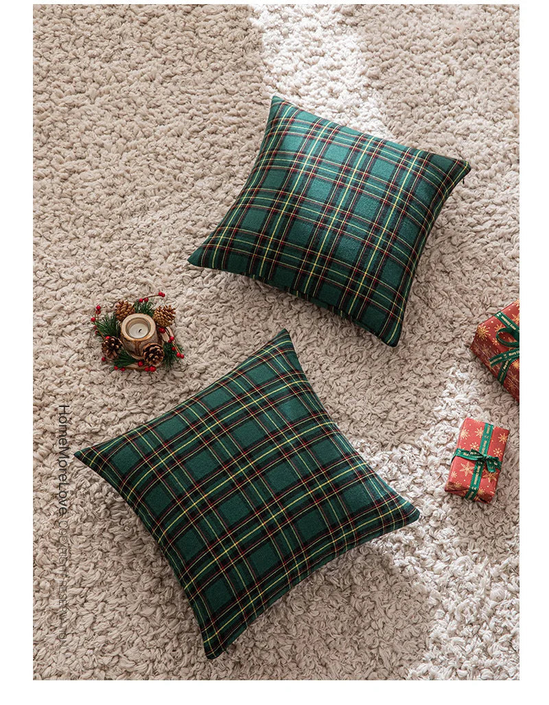 Two dark green tartan plaid decorative throw pillow covers resting on a beige textured surface.