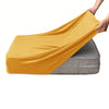 A hand is draping a bright yellow velvet stretchy sofa seat cover over a gray cushion.