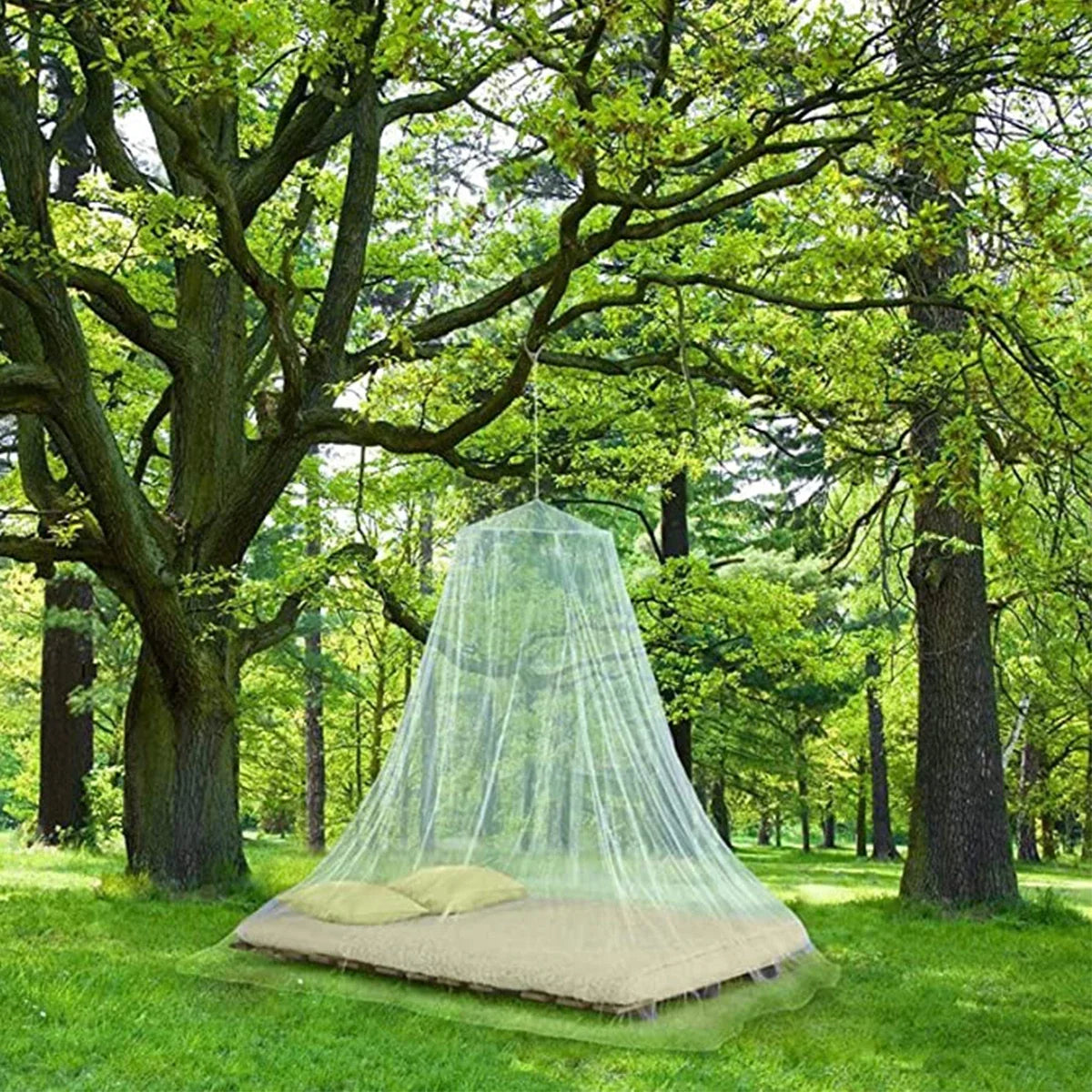 A green mosquito net dome suspended over a bed in a grassy outdoor setting.