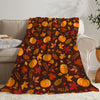 A dark orange and red autumn leaf pattern fleece throw blanket draped over a light colored sofa.