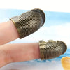 A close-up of an antique sewing thimble and needle protector set, featuring brass-colored metal protectors on a finger.