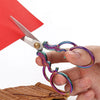 A pair of vintage stainless steel sewing scissors with iridescent purple and green handles resting on a wooden surface.