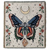 A throw blanket featuring a geometric butterfly design in earthy tones on a light background.