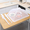A foldable mesh insect and fly protection cover is placed on a wooden table with food items underneath.