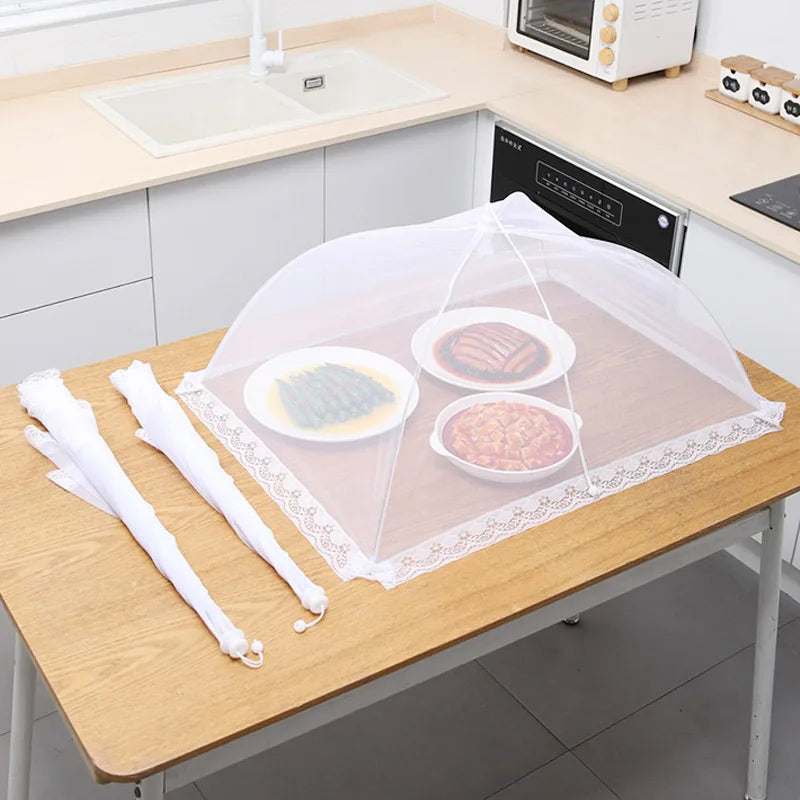 A foldable mesh insect and fly protection cover is placed on a wooden table with food items underneath.