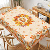 Fall harvest tablecloth featuring orange pumpkins and maple leaves on a wooden dining table.