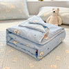 Light blue quilted blanket with a pattern of small cream-colored bears and stars resting on a white surface.