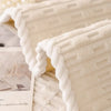 A close-up of a white, textured, quilted sofa cover with a braided trim.