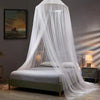 A sheer white dome mosquito net draped over a bed for home protection.