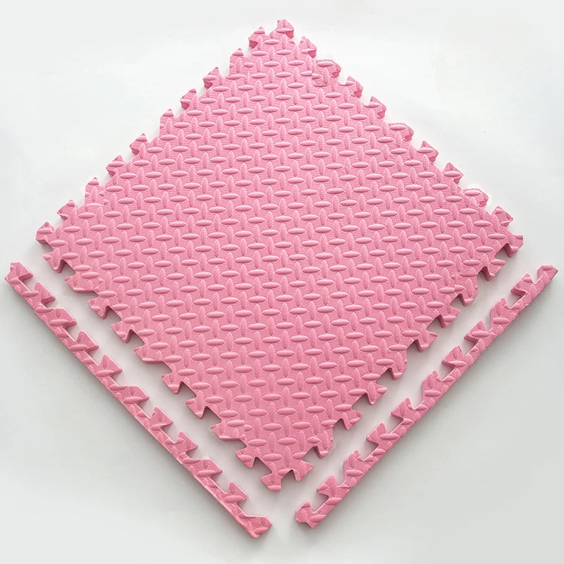 A pink soft interlocking foam play mat with a diamond pattern shown from above.