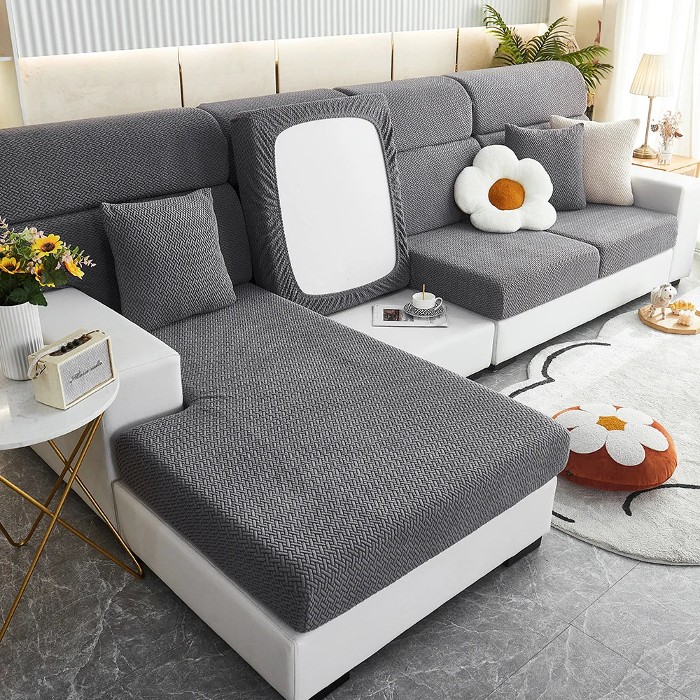 A modern gray Jacquard sofa slipcover with white cushions and a light wood accent table.