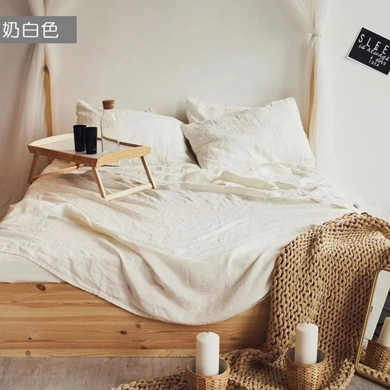 A white linen bedding set featuring a duvet and pillows displayed on a wooden bed frame.