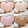 A set of pink and beige heart-shaped plush cushions shown in various angles on a light fabric background.