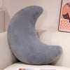 A soft gray moon-shaped throw pillow resting on a white surface.