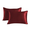 A pair of deep burgundy satin pillowcases lying flat.