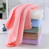 A stack of ten fluffy velvet cleaning face towels in various shades of pink, peach, and blue on a white surface.