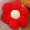 A bright red sunflower plush flower cushion resting on a light-colored fabric.