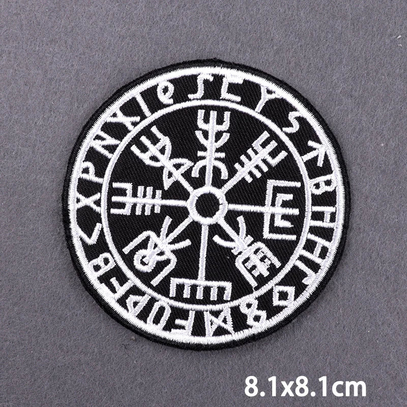 Black embroidered circular patch featuring various ancient symbols and letters on a gray background