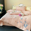 A pink embroidered duvet cover set featuring floral patterns and lace trim on a bed.