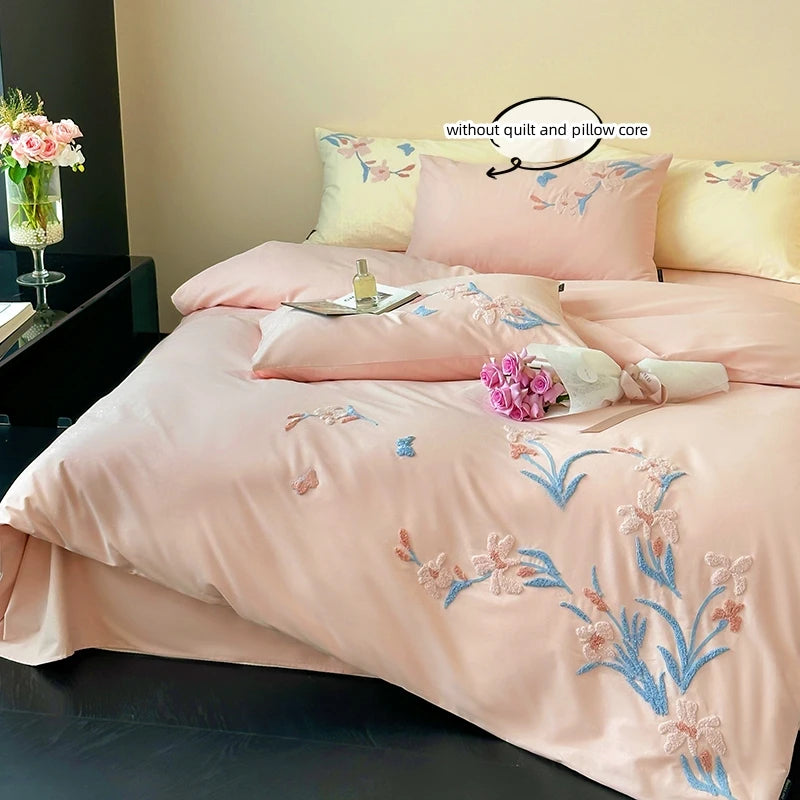 A pink embroidered duvet cover set featuring floral patterns and lace trim on a bed.