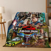 A fabric throw blanket featuring characters and dinosaurs from the Jurassic Park franchise.