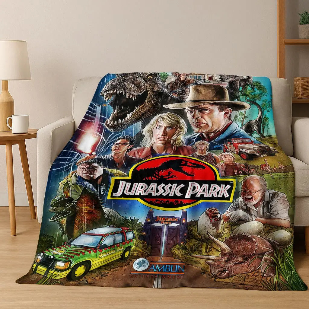 A fabric throw blanket featuring characters and dinosaurs from the Jurassic Park franchise.