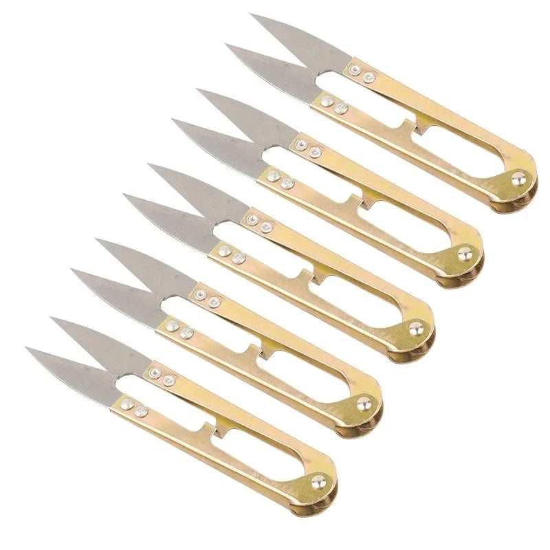 A set of four gold-colored U-shape sewing scissors used for cutting thread, yarn, fabric, and needlework.