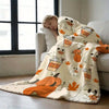 A white and orange flannel throw blanket featuring a pattern of cute cartoon pumpkins and coffee cups.